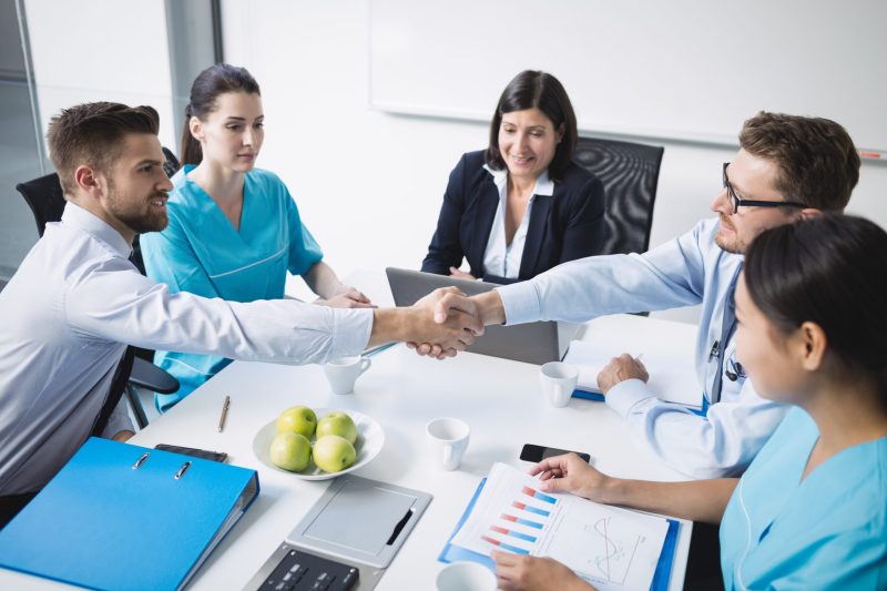 Doctors shaking hands with each other in meeting at conference room Doctors shaking hands with each other in meeting at conference room