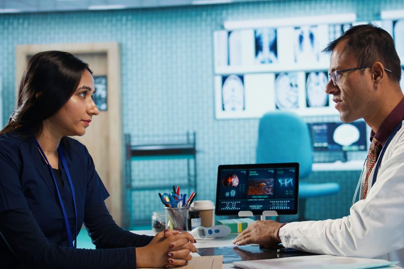 Physician meeting with patient to discuss medical test results in cabinet, using advanced diagnostic tools to interpret x ray scans, demonstrating a professional healthcare approach. Camera B.